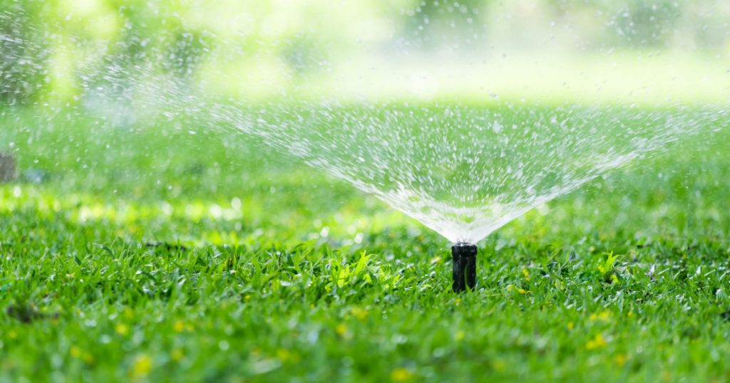 Automatic Garden Lawn sprinkler in action watering grass.
