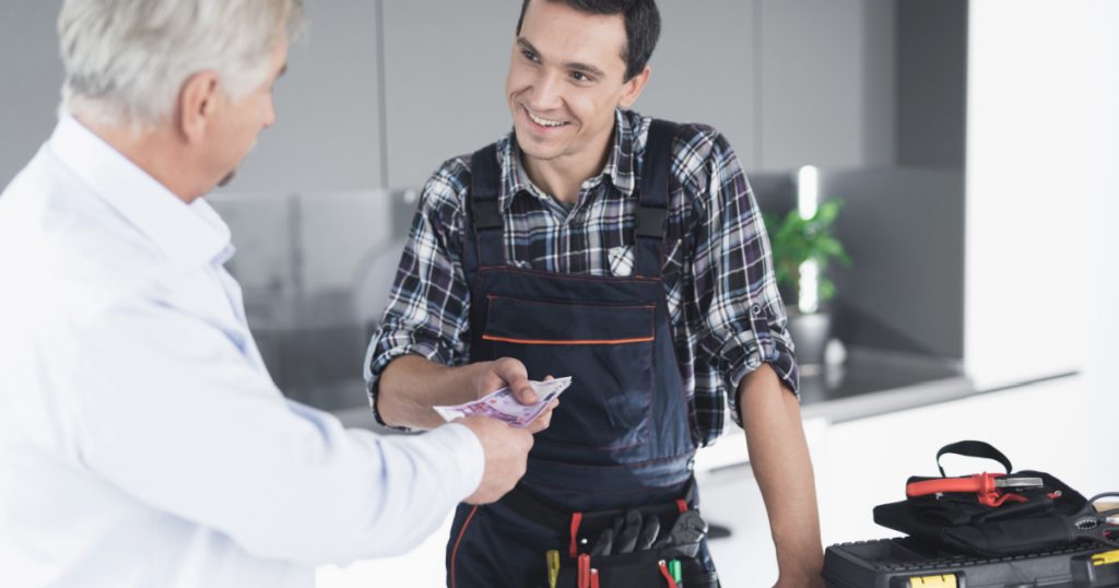 A plumber man communicates with a client who pays for the work done. The old man gives the plumber a fee. A black box for tools is next to it.
