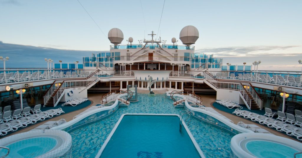 View of top deck of cruise ship with luxurious pools and spa facilities.
