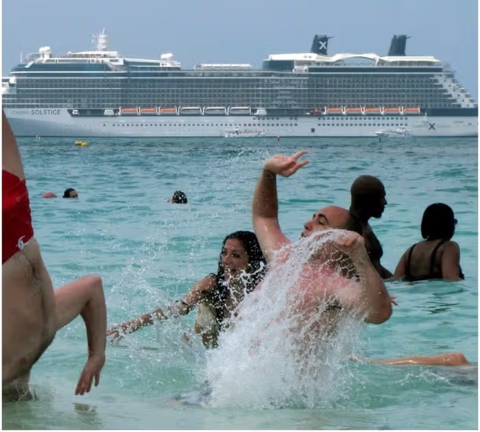 people swimmig in ocean near cruise ship