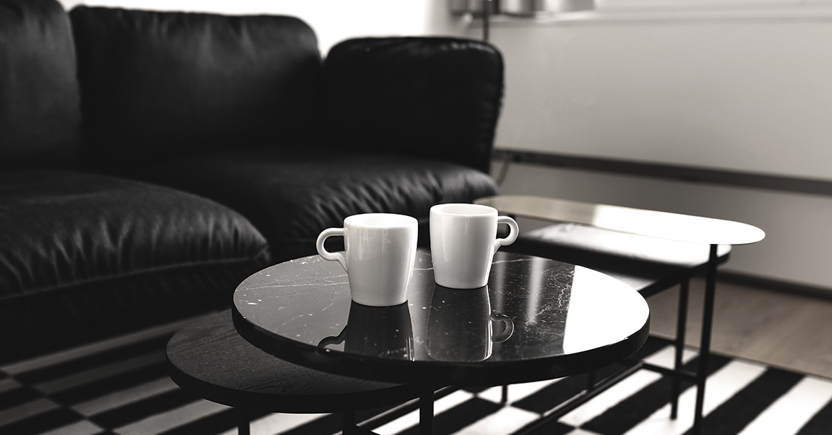 black couch and black coffee table with 2 white cups on it