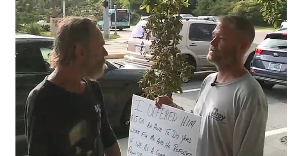 man holding sign offering work to panhandler 