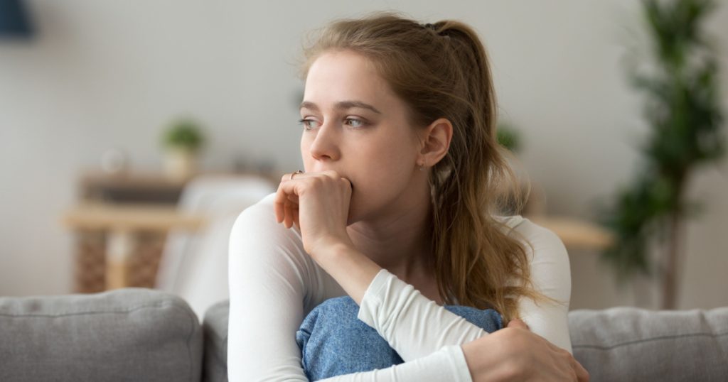Head shot woman anxious worried woman sitting on couch at home. Frustrated confused female feels unhappy, problems in personal life, quarrel break up with boyfriend and unexpected pregnancy concept
