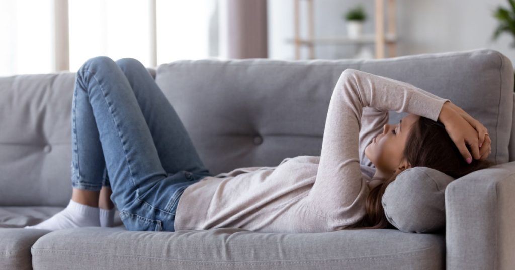 teen girl lyign on couch headache anxiety