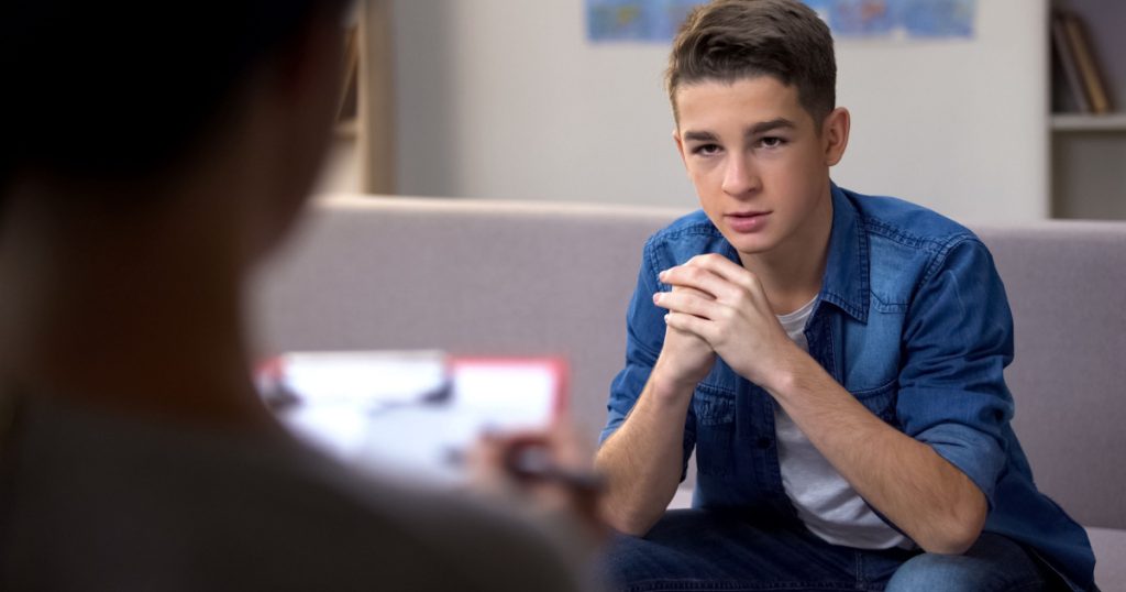Anxious teenager visiting psychologist for personal therapy session, problems
