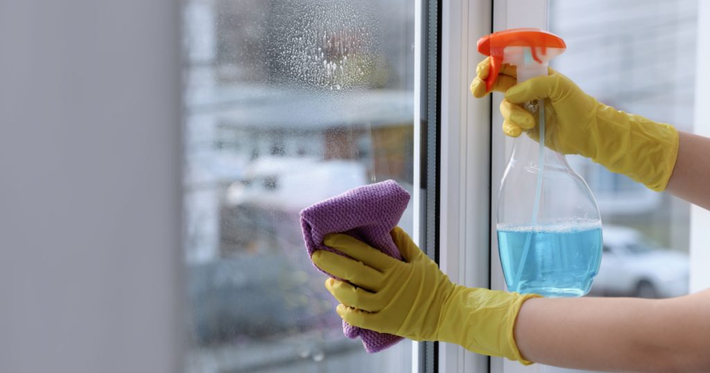 Woman cleaning window at home, closeup. Household chores
