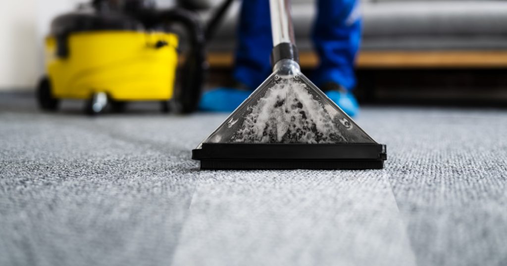 Janitor Cleaning Carpet With Vacuum Cleaner At Home
