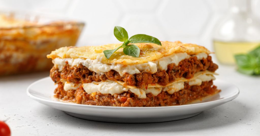 Lasagna. Homemade Italian Lasagne with bolognese meat sauce, cheese and basil on white plate. Close up.
