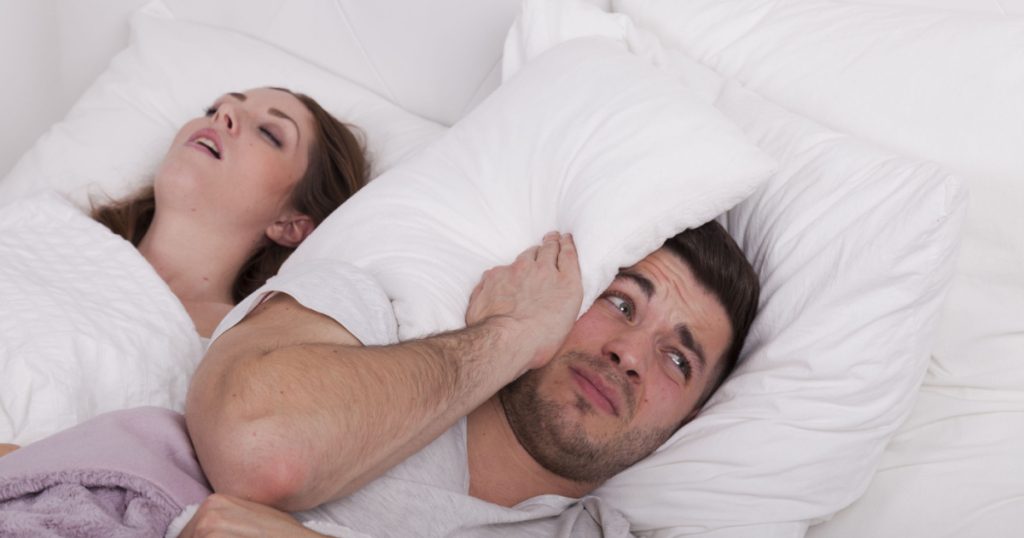 man has problems fall asleep while woman snores in bed
