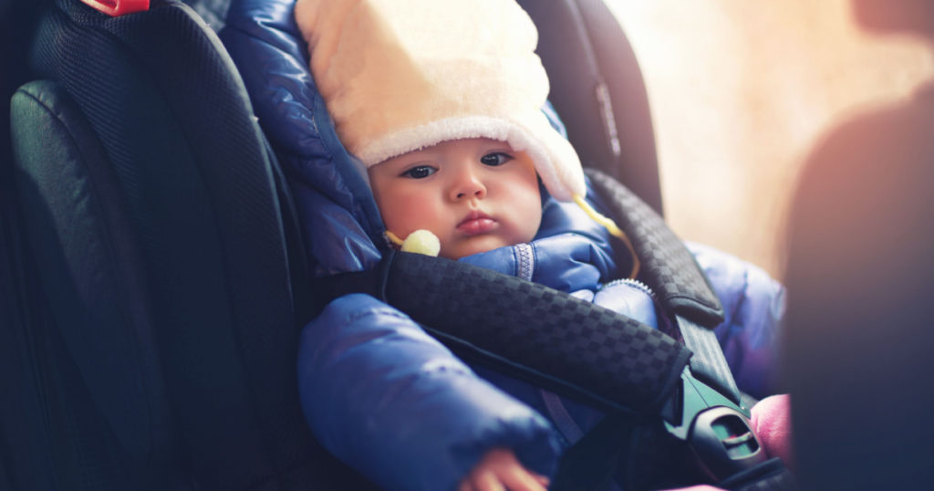 Adorable little girl sitting in car in winter clothes
