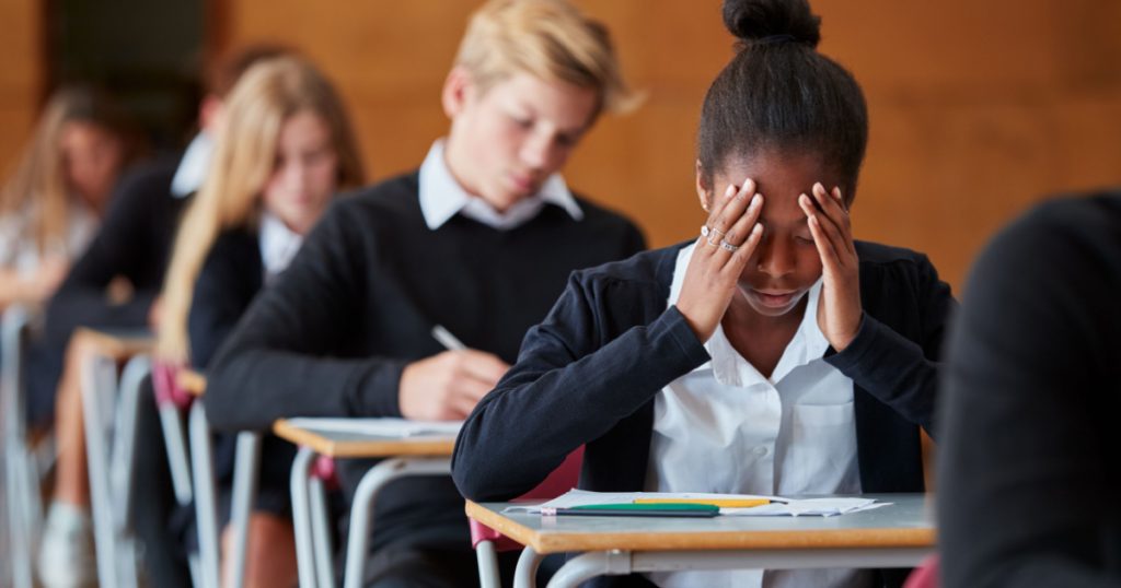 Anxious Teenage Student Sitting Examination In School Hall
