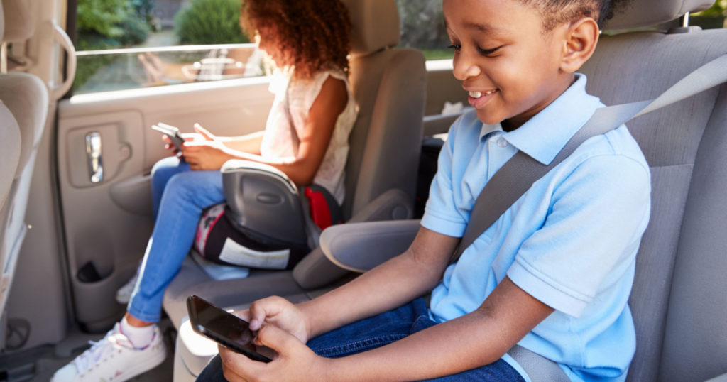 Children Using Digital Devices On Car Journey
