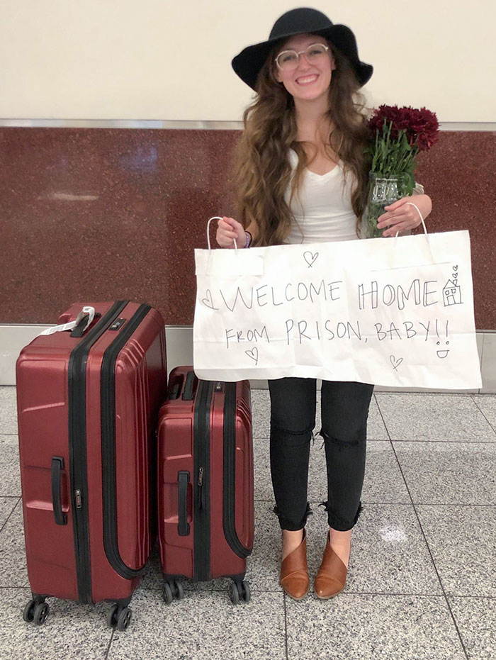 Woman welcoming husband home with funny sign