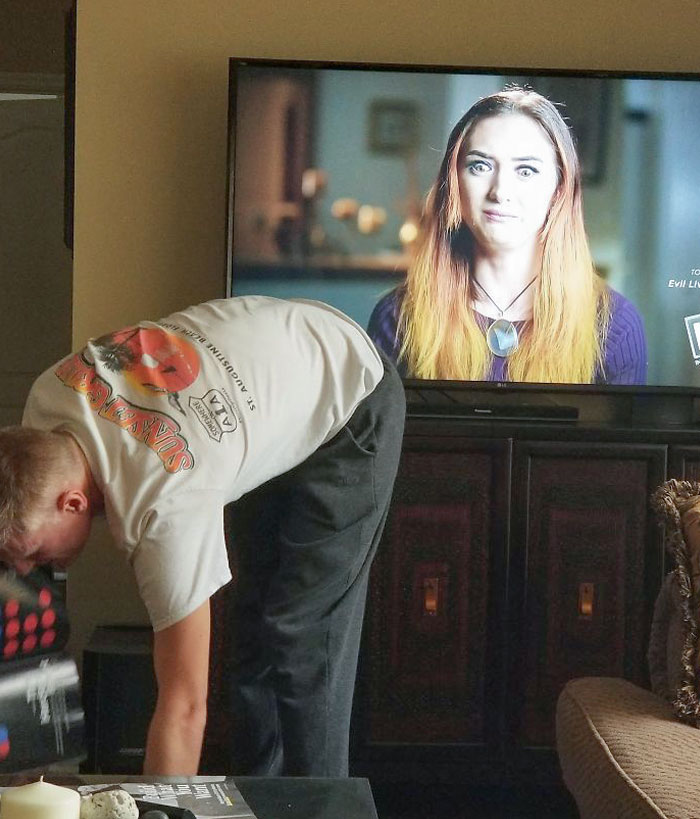 Badly timed photograph of person on TV lookingat man bent over