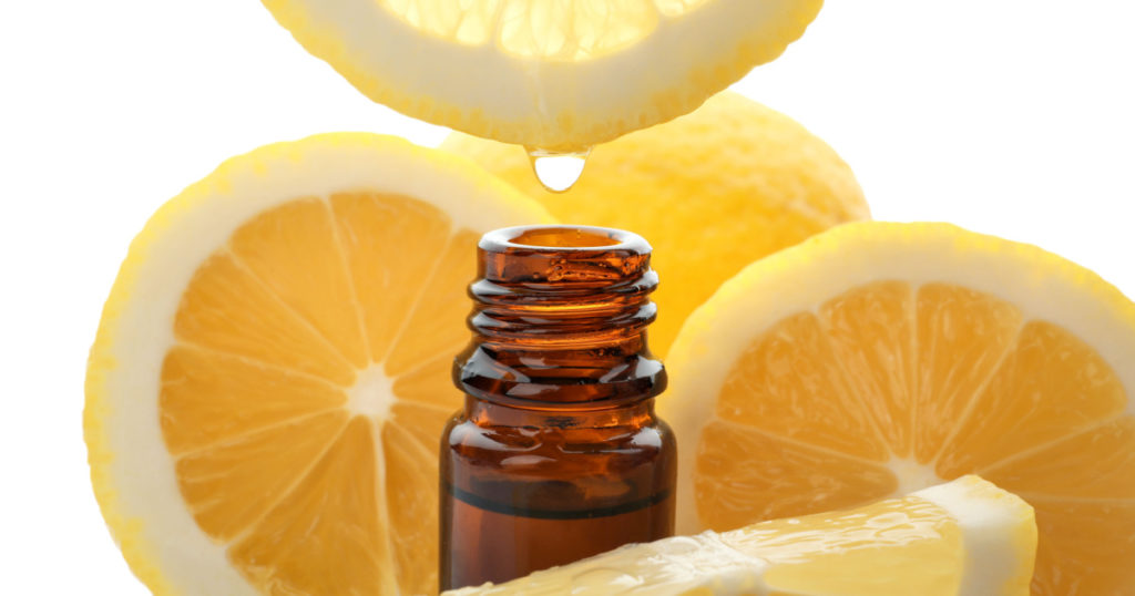 Dripping citrus essential oil into bottle on white background
