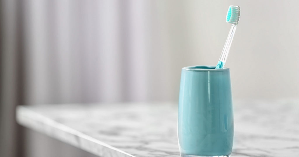 Cup with toothbrush on table. Dental care

