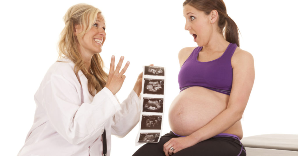 a doctor showing her pregnant patient that she is going to have triplets.
