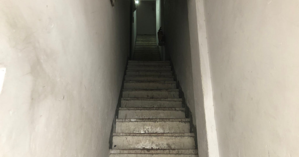 Dark, tall and narrow concrete stairs
