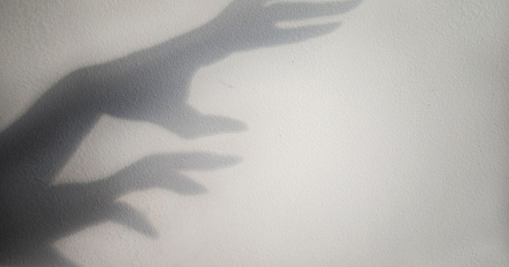 big monster claw shadow on wall. Horror hand shadow on a white background, copy space.

