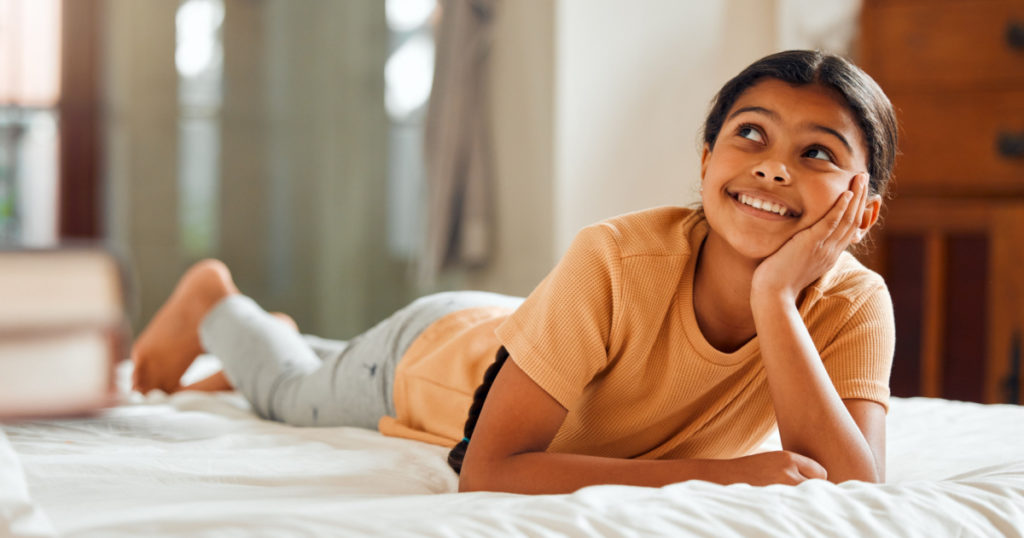 Fantasy, bed and black girl thinking, ideas and relax on weekend, happiness and summer break. African American female child, young lady or daydreaming, imagination and thought with wonder and bedroom
