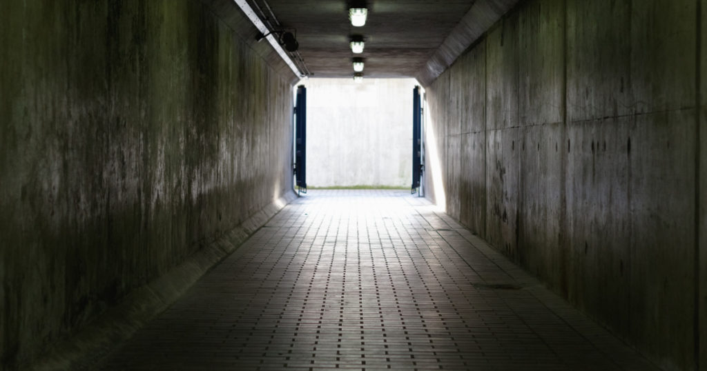 Thames Barrier passageway in London, a dim and concrete corridor leading to bright exit
