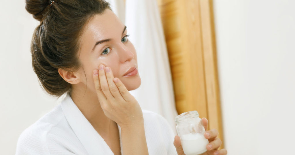 Woman is moisturizing her skin with a coconut oil
