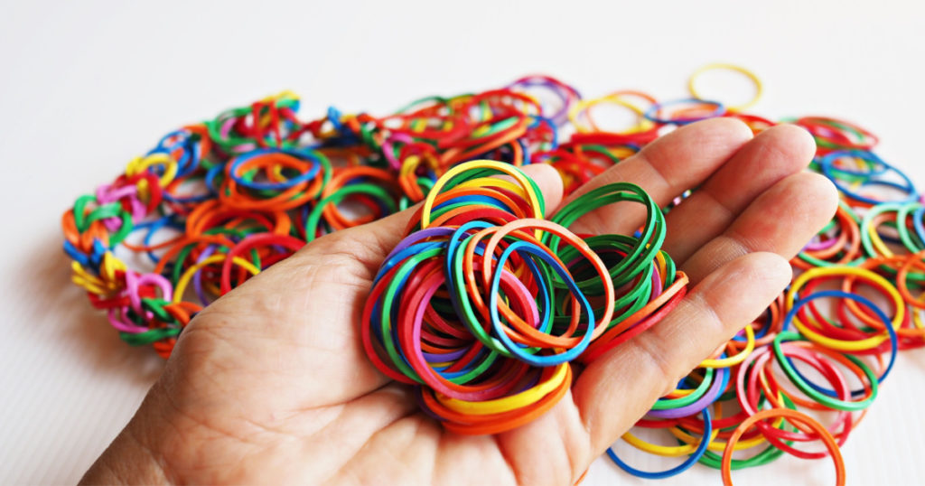 Holding a pile of colorful rubber bands in hand.
