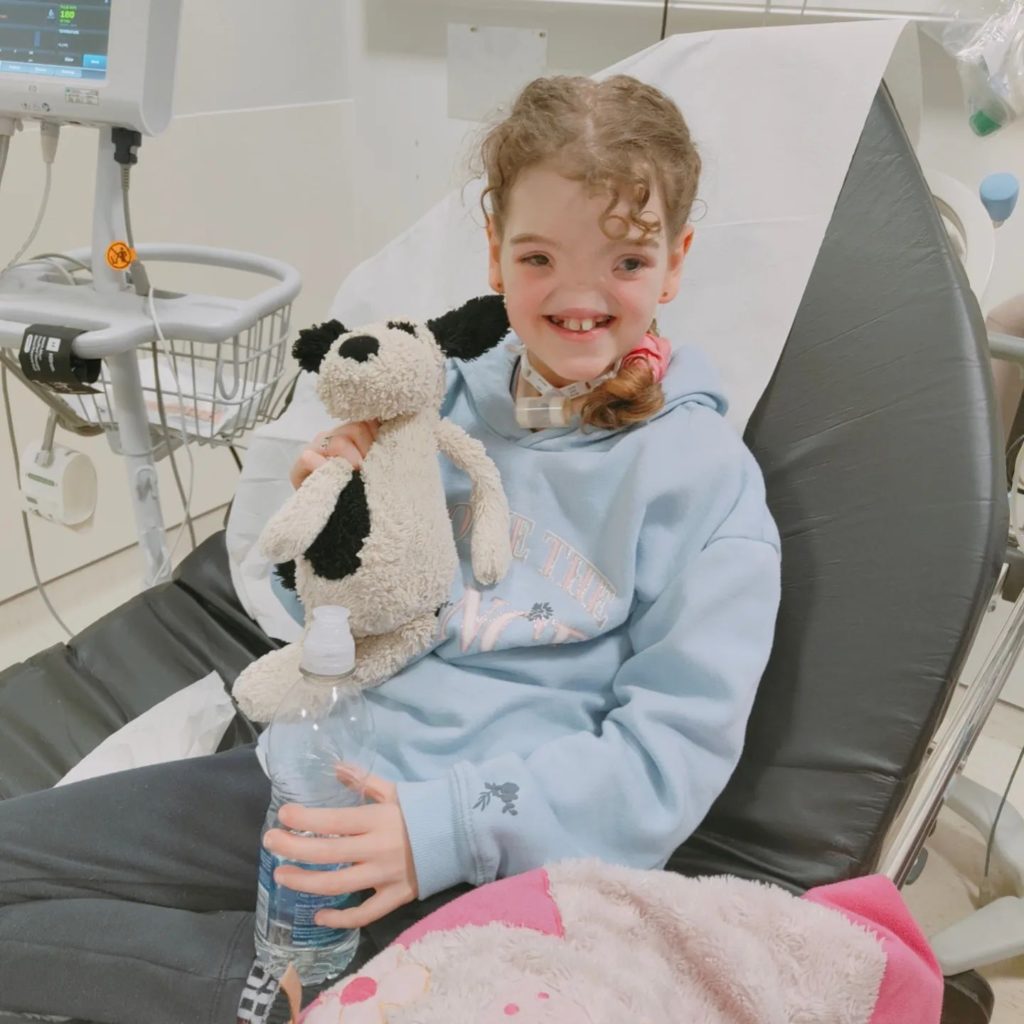 Tessa Evans in hospital with her stuffed toy dog. 
