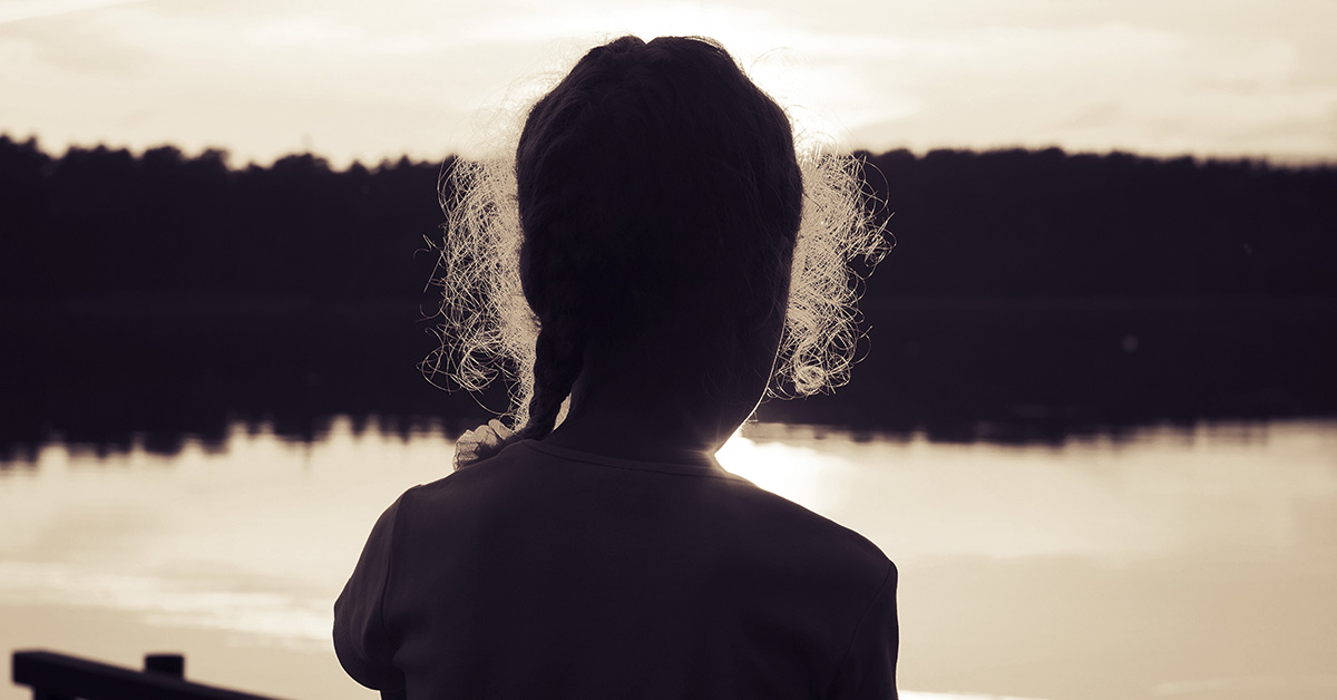 silhouette of girl looking out onto a lake
