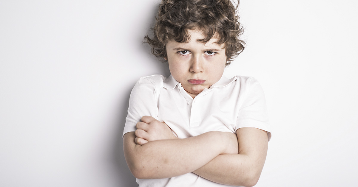 young disgruntled boy with arms crossed