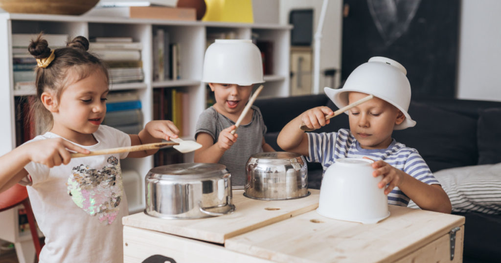 kids having fun playing on kitchen pans at home
