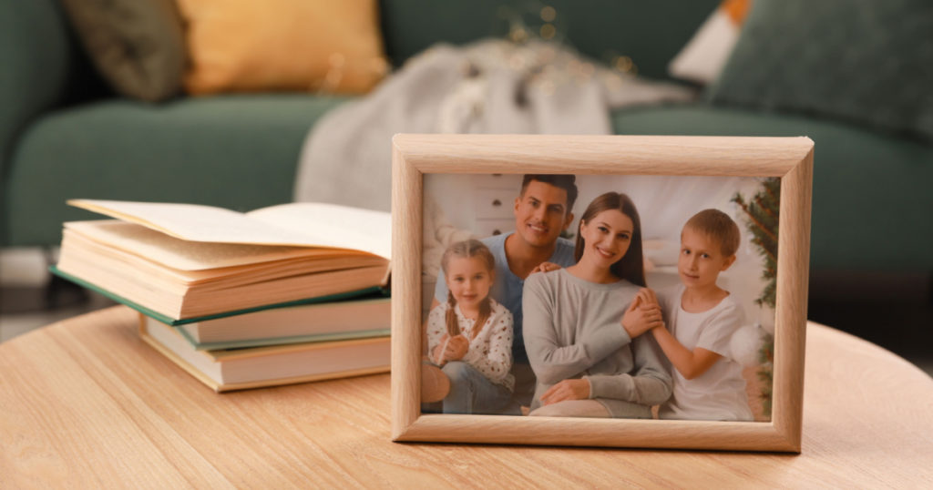 Framed family photo and books on wooden table indoors