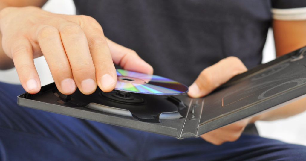 closeup of a young man pulling a DVD or a CD out of its case