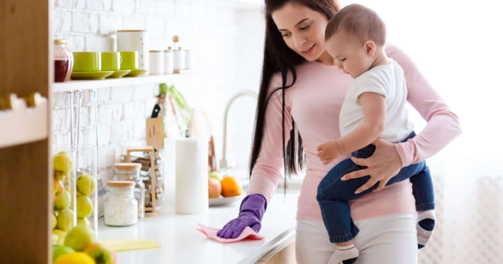 Domestic chores at maternity leave. Young mother with baby boy cleaning kitchen at home, free space