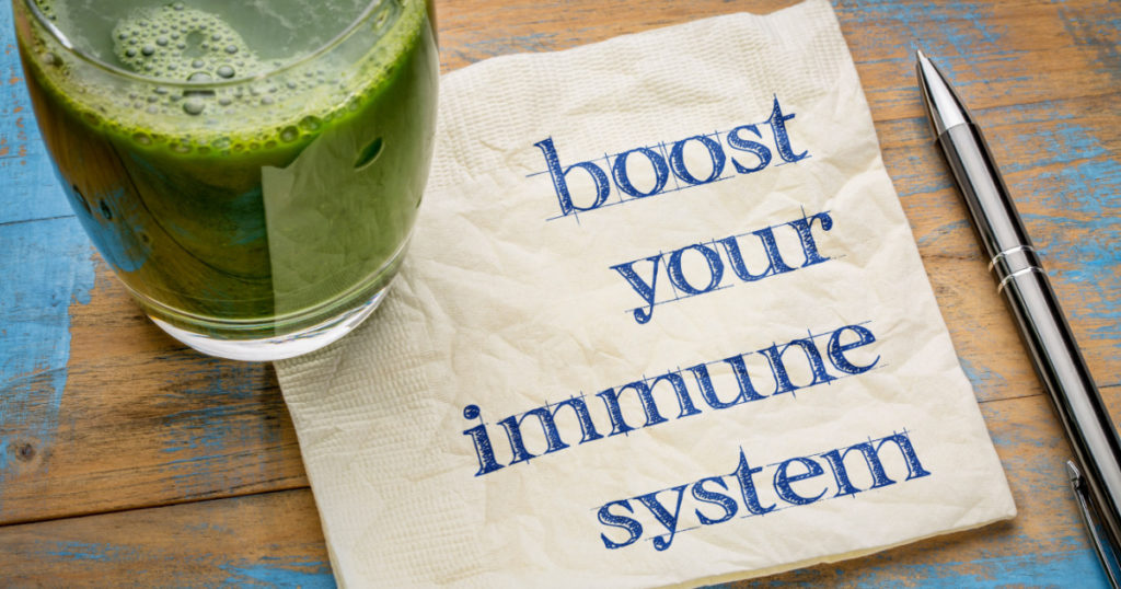 boost your immune system - inspirational handwriting on a napkin with a glass of fresh, green, vegetable juice, healthy lifestyle and wellbeing concept
