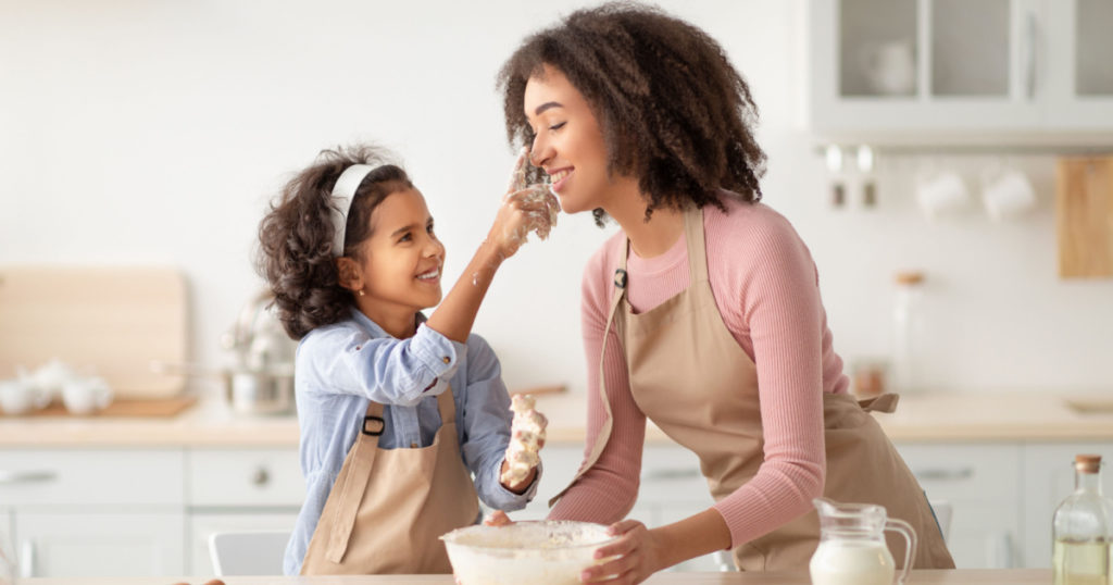 Black woman and daughter cooking and playing with flour