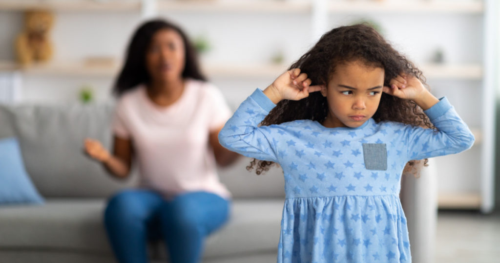 Family argument. Sad offended black girl covering ears, not wanting to listen to her mother's scloding, free space. Millennial woman having fight with her child, quarelling at home

