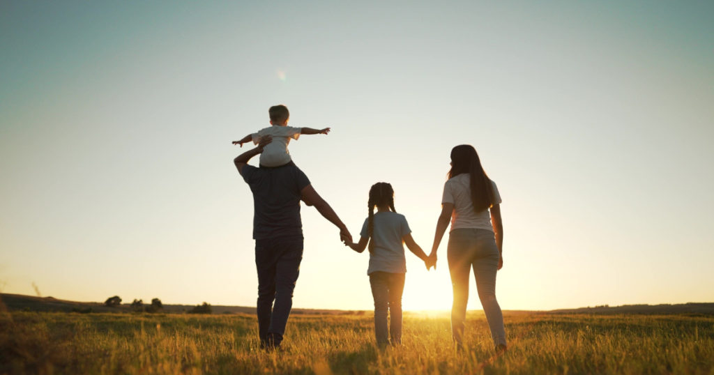 Happy family walk in field in nature.Parents and children are free and active people in nature.Healthy and cheerful family at picnic in the park.Summer walk in the park at sunset.Parents and children