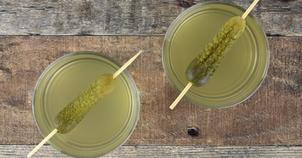 Cucumber pickle or pickle juice in a glass on a wooden background. Top view. Trend drink. The concept of sports nutrition.
