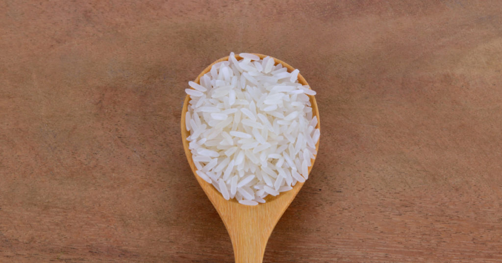milled rice on wood spoon and Wooden Floor