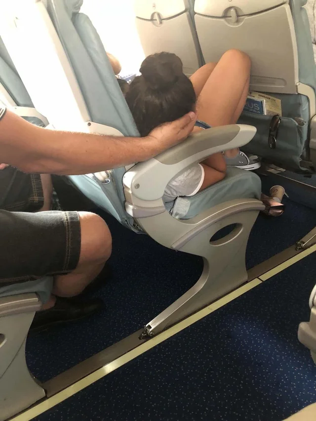 Father cradling his daughter's head to let her sleep during the flight.