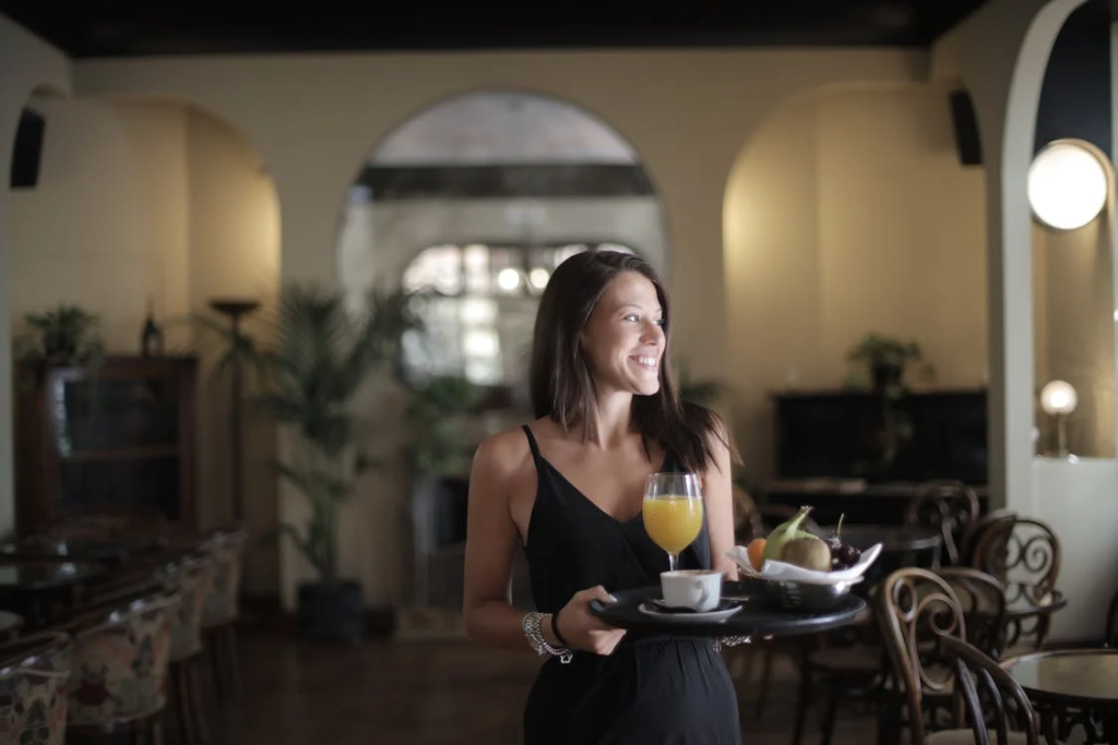 Happy woman carrying tray with breakfast in hotel restaurant
