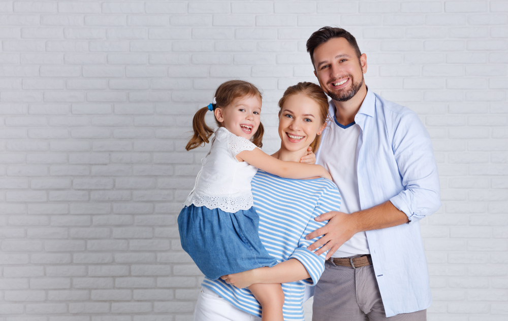 happy family mother father and child daughter near an empty brick wall