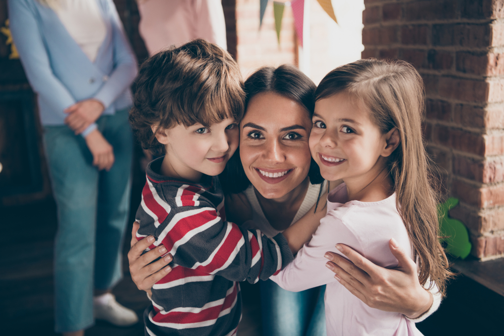 Close up photo of gathered relatives in decorated home house aunt cuddle to little girl boy children nephew niece looking gladly on camera missed little kids