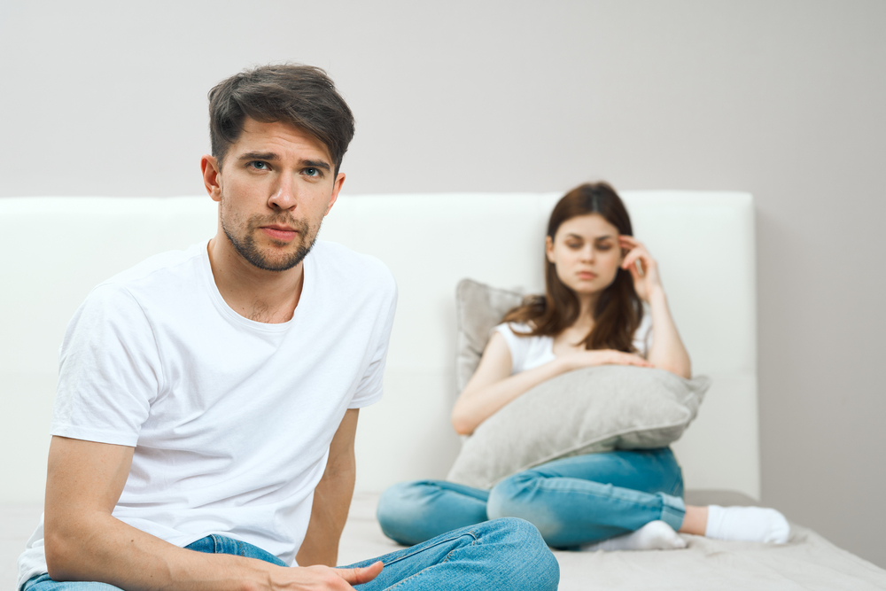 Man and woman on the couch are looking at the camera, family is having problems