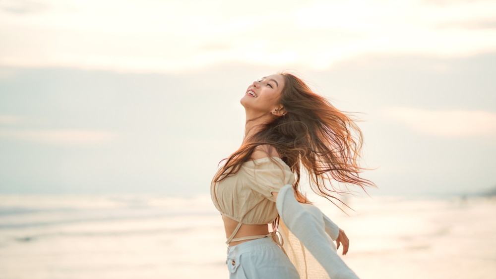 Side view of young asian woman with freedom on the sea beach at golden sunset, Female tourist on seaside summer vacation