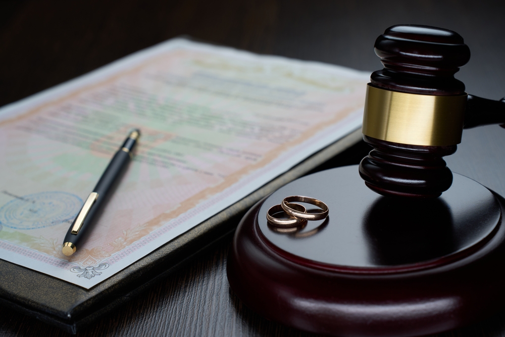 Divorce decree or marriage contract. Judge gavel with wedding rings and divorce decree. Marital agreement, legalities of divorce documents