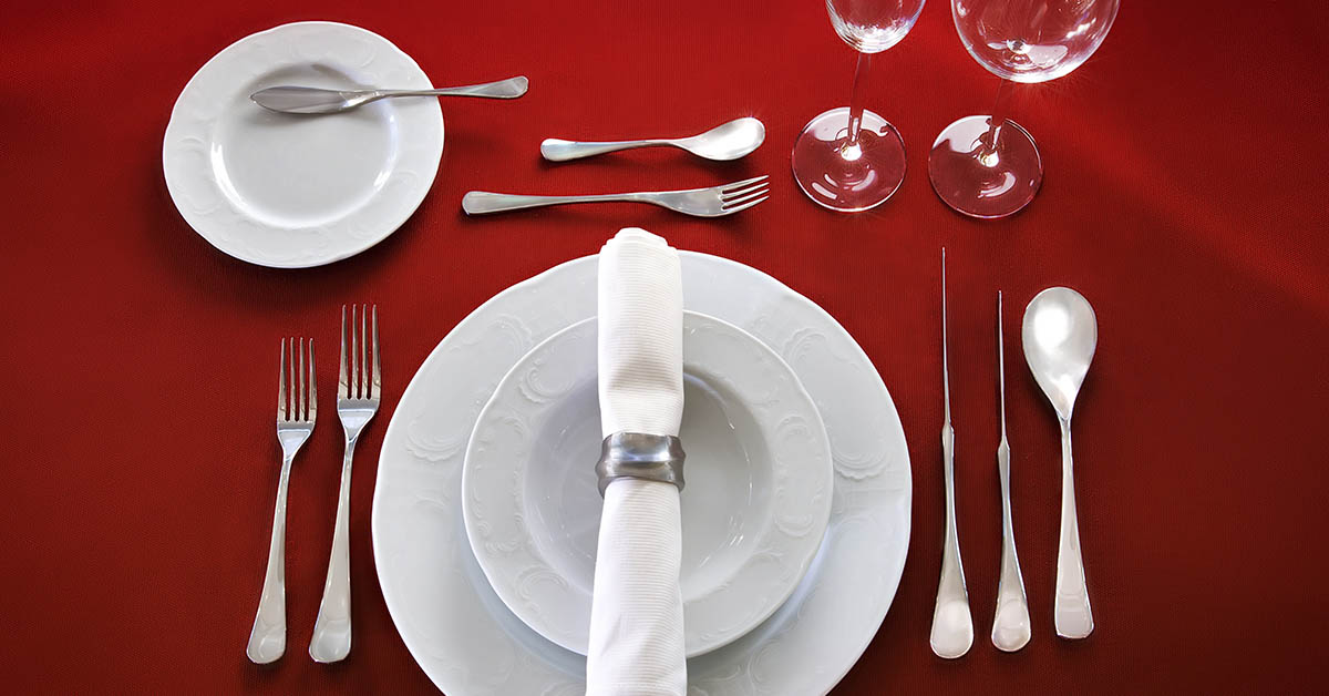 Fine dining plates and cutlery on red tablecloth