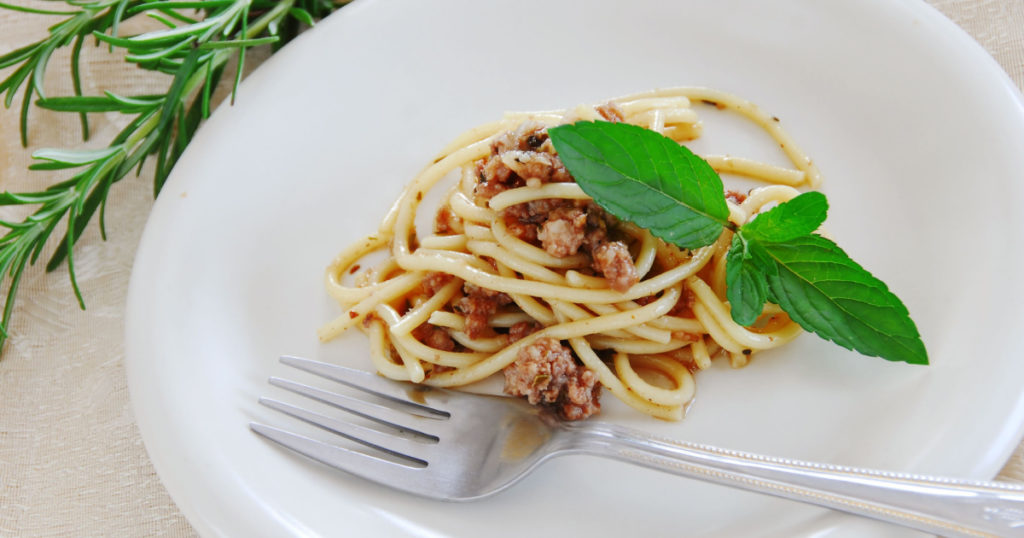 small portion of spaghetti mixed with minced meat served on white plate