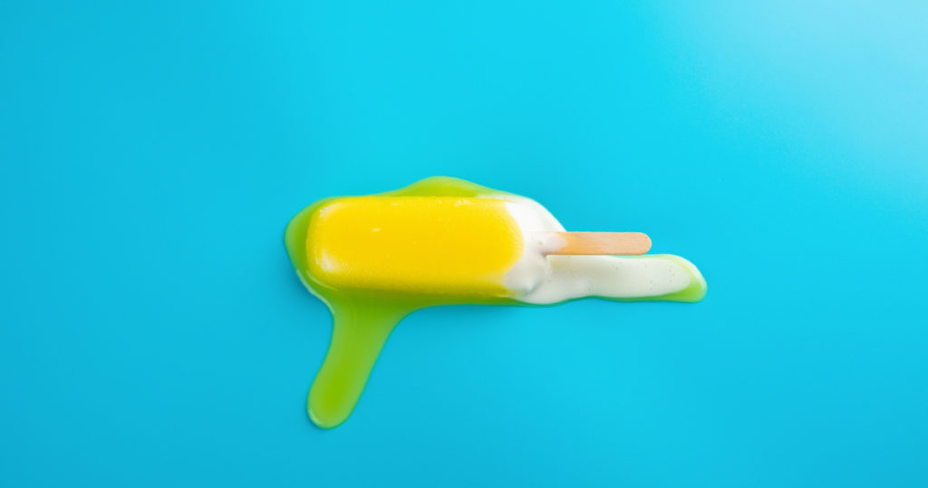 yellow popsicle in a melting process on blue background